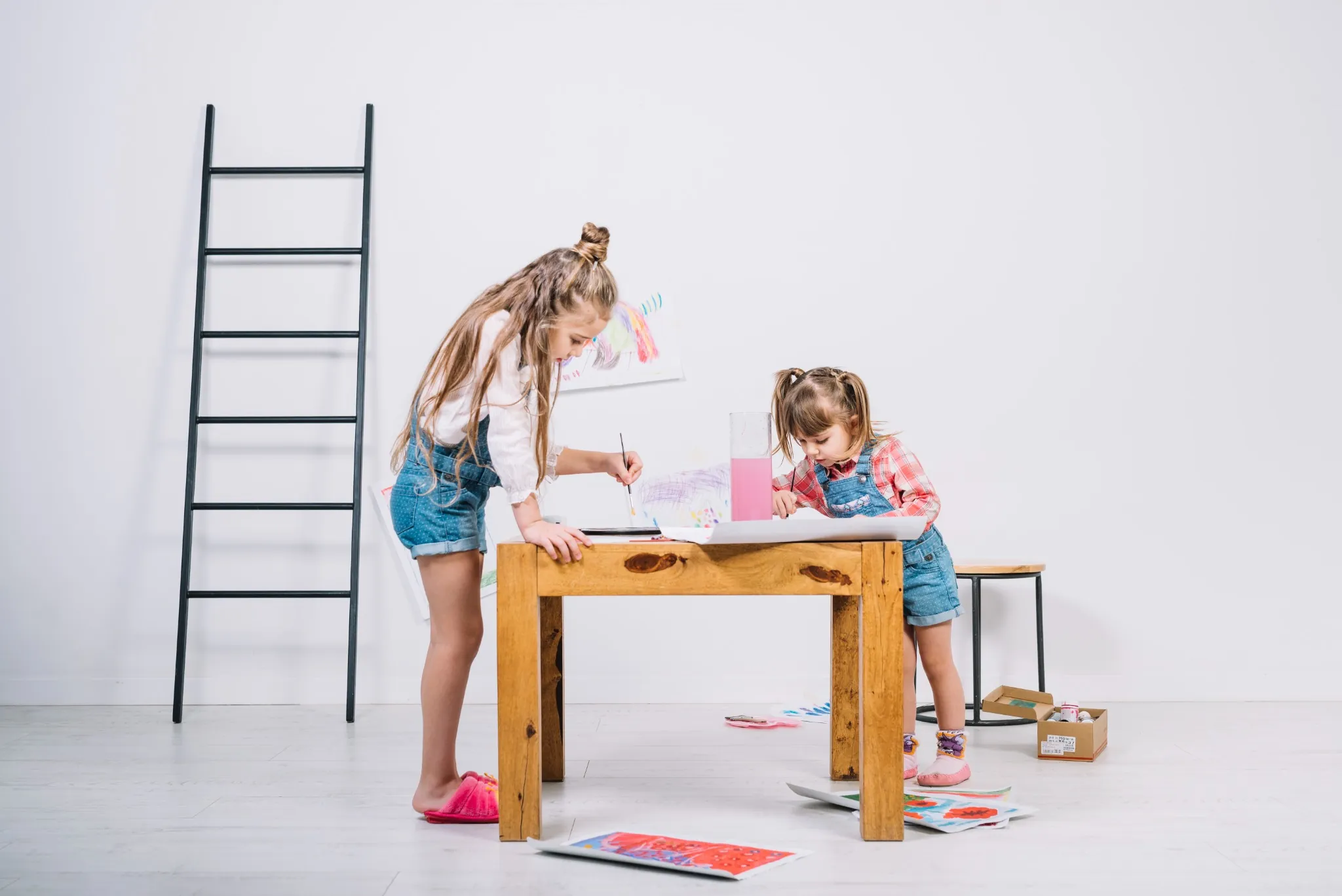 two-little-girls-painting-with-aquarelle-table
